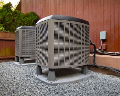 Two air conditioners are sitting on the ground.